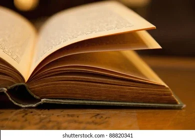 An open book on a wooden table in warm light
